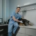 A Veterinarian Sitting Beside a Black Dog Lying on the Table